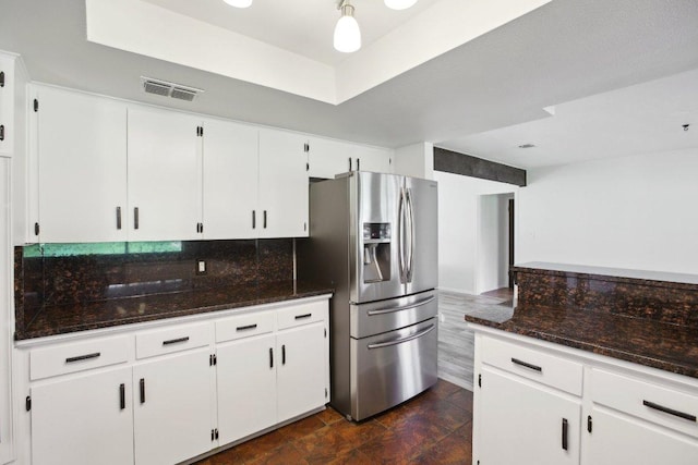 kitchen featuring visible vents, decorative backsplash, dark stone countertops, white cabinetry, and stainless steel refrigerator with ice dispenser