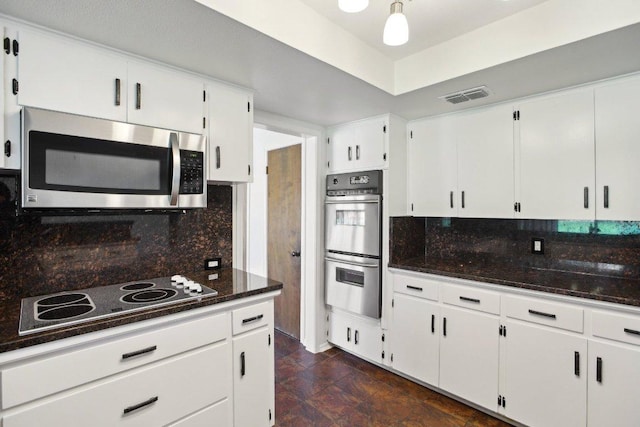 kitchen featuring tasteful backsplash, visible vents, dark stone countertops, stainless steel appliances, and white cabinetry