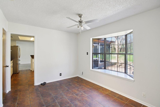 empty room with ceiling fan, baseboards, and a textured ceiling