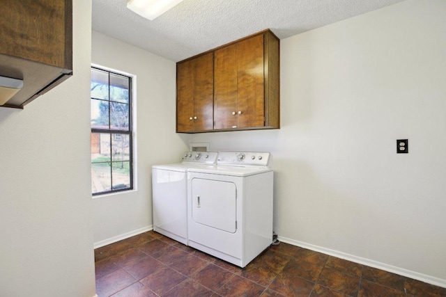 washroom featuring baseboards, plenty of natural light, cabinet space, and washer and dryer