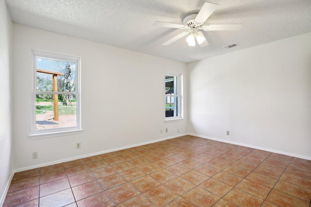 empty room with light tile patterned floors, ceiling fan, plenty of natural light, and visible vents