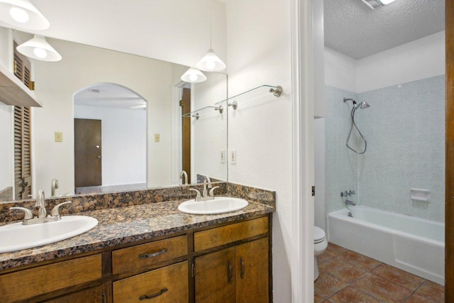 full bathroom with tile patterned flooring, a sink, a textured ceiling, and toilet