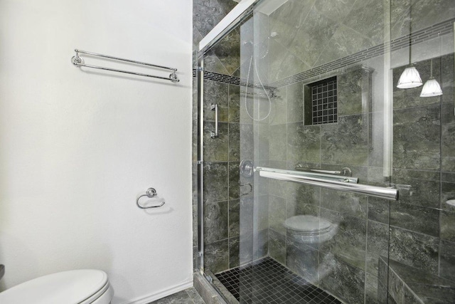 bathroom with toilet, a shower stall, and baseboards