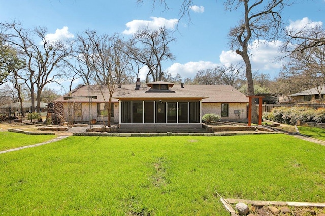 rear view of house featuring a sunroom and a lawn