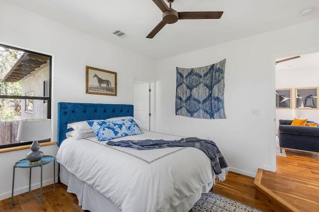 bedroom featuring ceiling fan, wood finished floors, visible vents, and baseboards