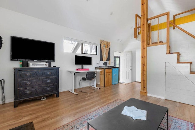 living room with light wood-style floors, baseboards, and stairway