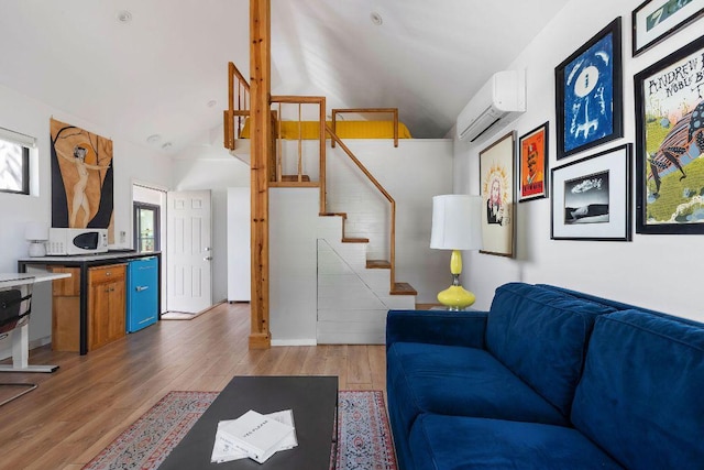 living room with a wall mounted air conditioner, light wood finished floors, and stairs