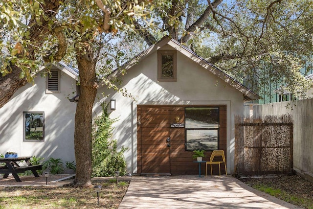 view of front of home featuring fence, a patio, and stucco siding