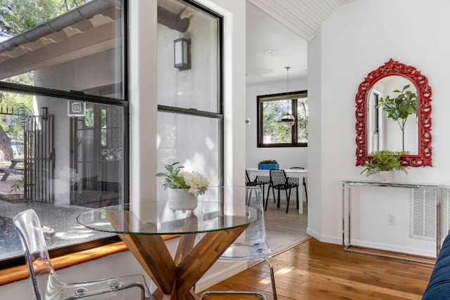 dining space featuring vaulted ceiling, baseboards, and wood finished floors