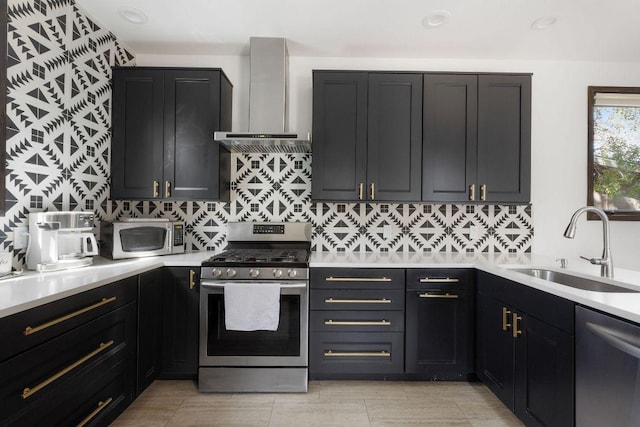 kitchen with decorative backsplash, stainless steel appliances, light countertops, wall chimney range hood, and a sink