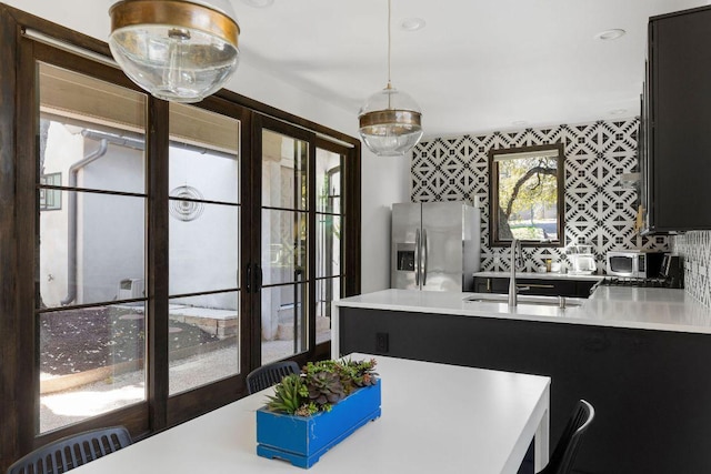 kitchen featuring a sink, stainless steel fridge, decorative backsplash, and light countertops