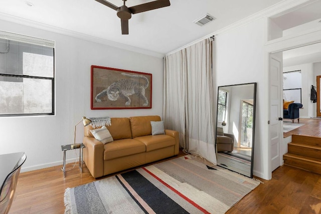 living room with visible vents, wood finished floors, and ornamental molding