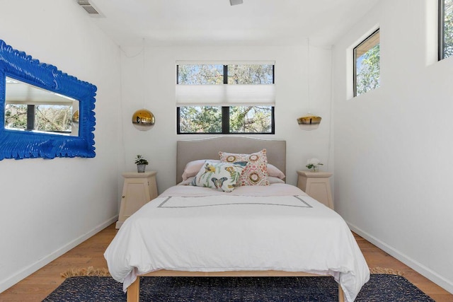 bedroom with wood finished floors, visible vents, and baseboards