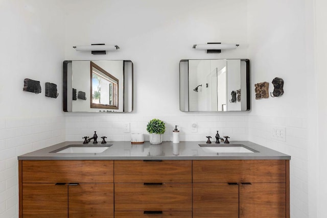 full bathroom featuring double vanity, tile walls, and a sink