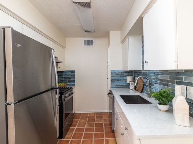 kitchen with visible vents, appliances with stainless steel finishes, ventilation hood, light countertops, and a sink