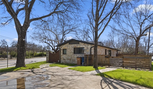 exterior space with a fenced front yard, stone siding, and a gate