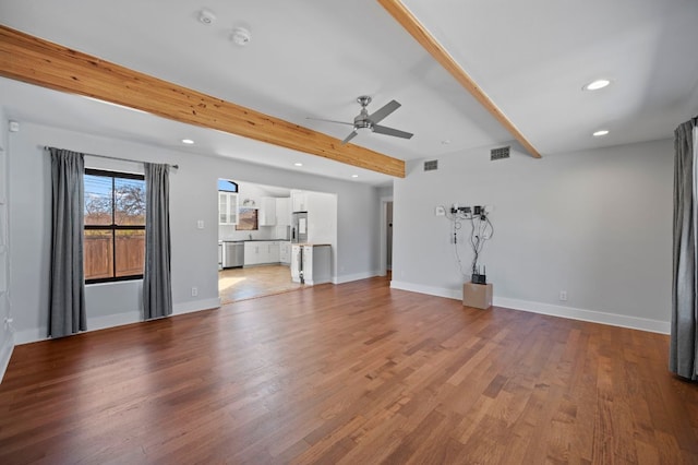 unfurnished living room featuring beamed ceiling, light wood-style floors, visible vents, and baseboards