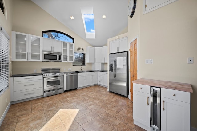 kitchen with white cabinetry, wine cooler, appliances with stainless steel finishes, a skylight, and glass insert cabinets