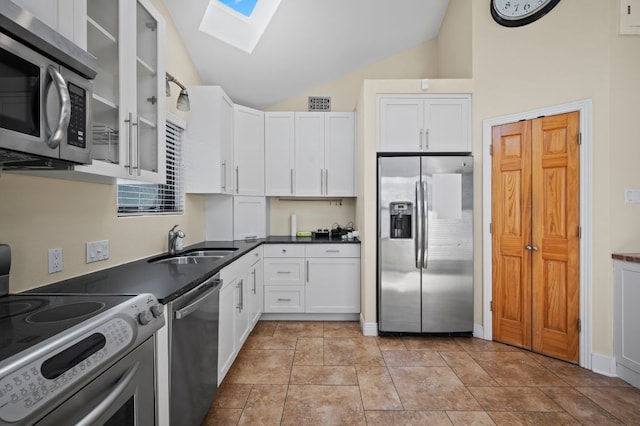 kitchen with a sink, dark countertops, stainless steel appliances, white cabinets, and glass insert cabinets