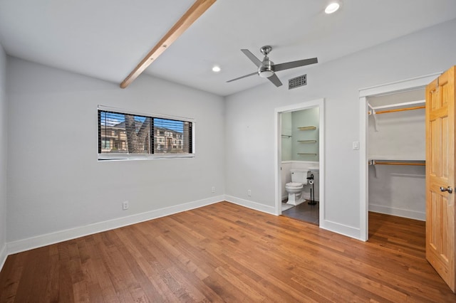 unfurnished bedroom with visible vents, wood finished floors, baseboards, and a walk in closet