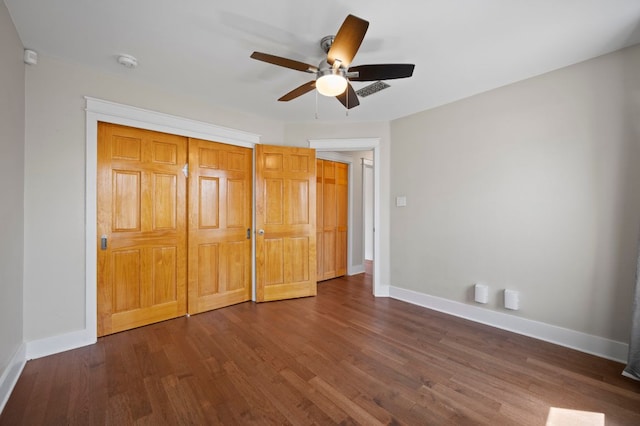 unfurnished bedroom with dark wood-type flooring, a ceiling fan, baseboards, and a closet