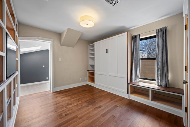 unfurnished bedroom with visible vents, baseboards, and wood finished floors