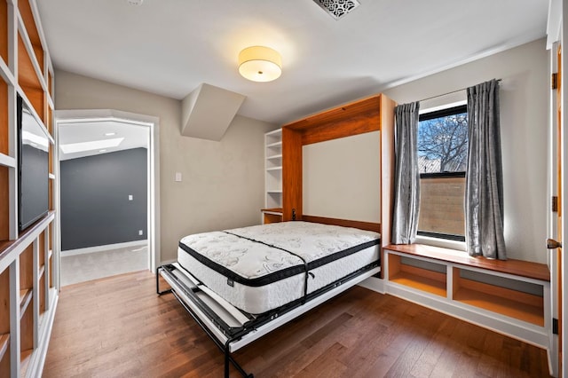 bedroom with visible vents, baseboards, and wood finished floors