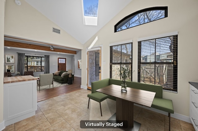 dining area with visible vents, baseboards, light tile patterned floors, a skylight, and high vaulted ceiling