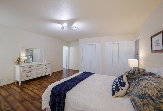 bedroom with wood finished floors, visible vents, and multiple closets