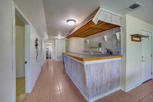 bar with visible vents, vaulted ceiling, a textured ceiling, and light tile patterned flooring