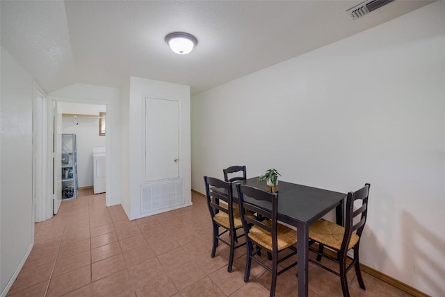 tiled dining area with washer / dryer, baseboards, and visible vents