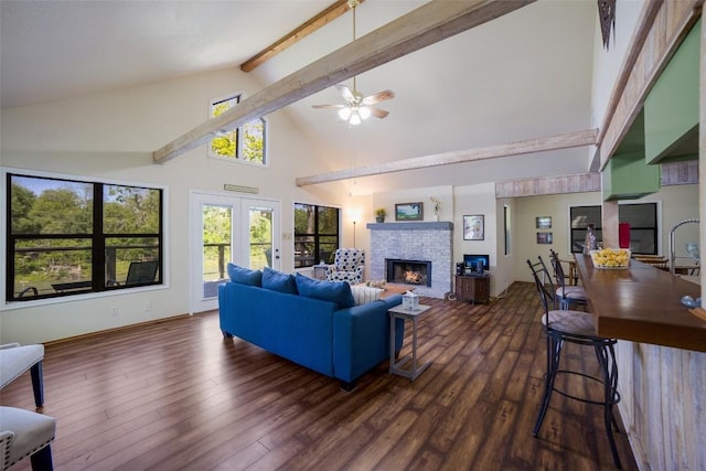 living area featuring a ceiling fan, dark wood-style flooring, a fireplace, high vaulted ceiling, and beam ceiling