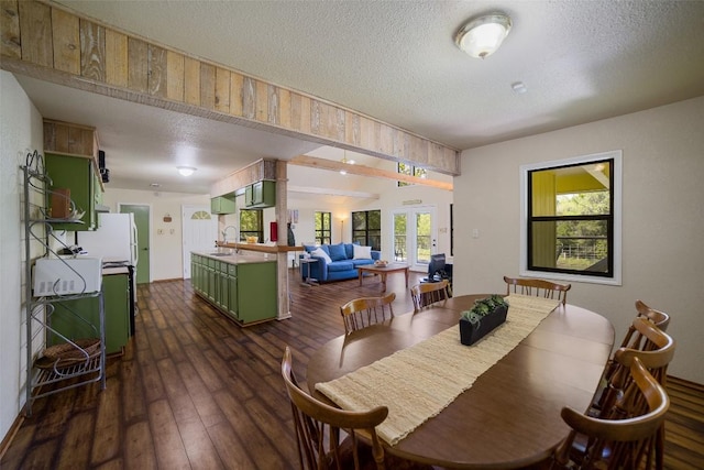 dining space with a textured ceiling, dark wood-type flooring, and french doors