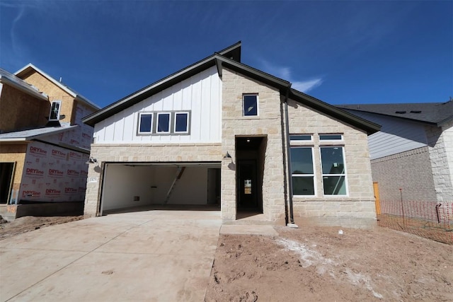 view of front of property with stone siding, board and batten siding, and concrete driveway