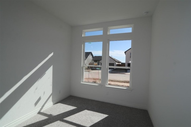 spare room featuring carpet floors and baseboards