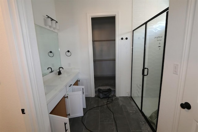 full bath with a walk in closet, double vanity, a sink, a shower stall, and tile patterned floors