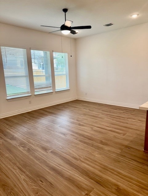 spare room featuring baseboards, a ceiling fan, wood finished floors, and visible vents