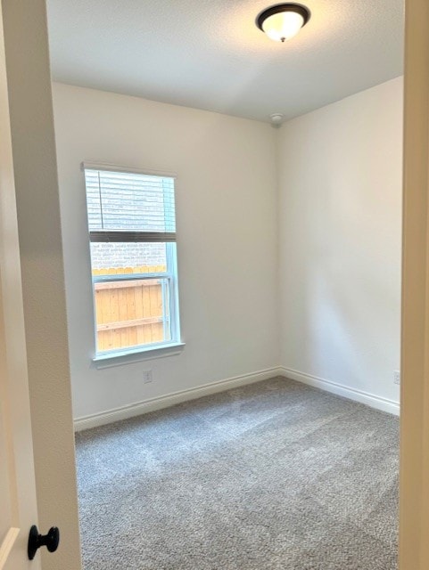 carpeted spare room featuring baseboards