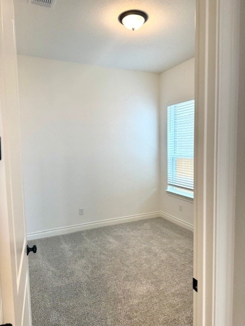 carpeted spare room featuring baseboards, a textured ceiling, and visible vents