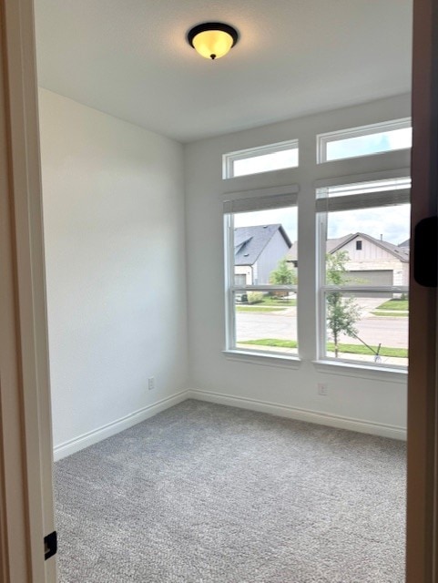 carpeted spare room with baseboards and a healthy amount of sunlight