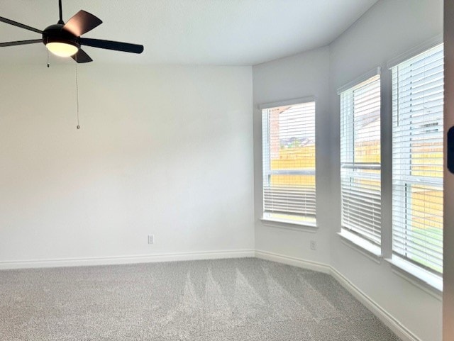 carpeted empty room with baseboards and a ceiling fan