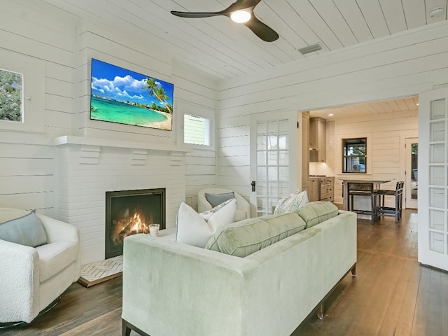 living room featuring dark wood-type flooring, wooden ceiling, a fireplace, and visible vents