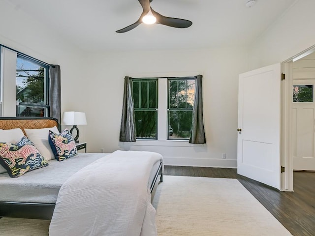 bedroom featuring baseboards, dark wood finished floors, and a ceiling fan