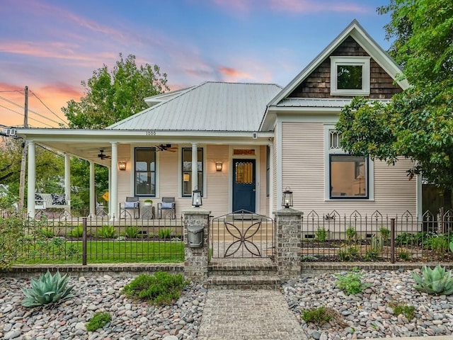 view of front of house featuring covered porch, metal roof, a fenced front yard, and a ceiling fan