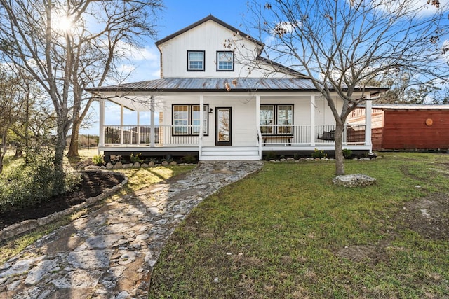 country-style home with covered porch, metal roof, and a front lawn