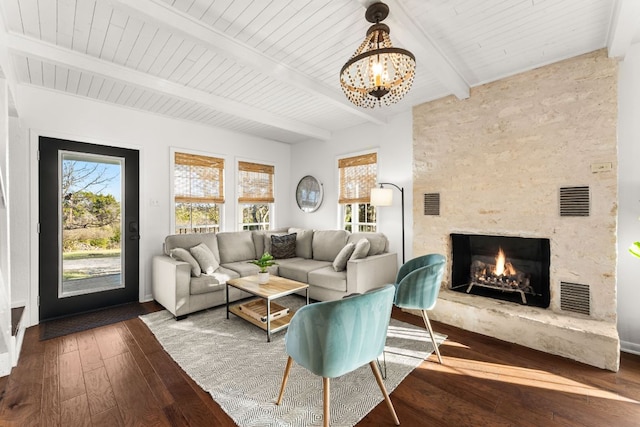 living room with visible vents, beamed ceiling, a stone fireplace, and hardwood / wood-style floors