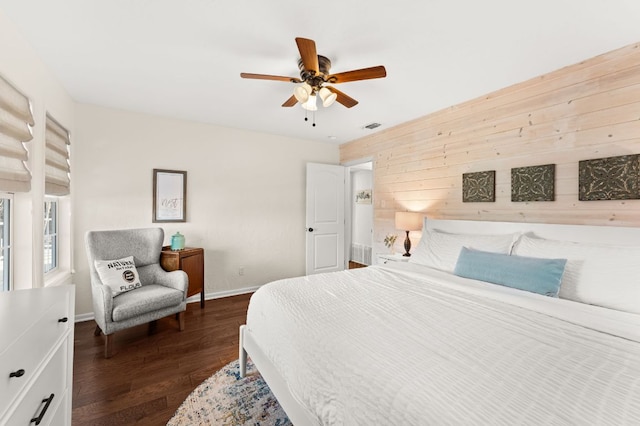 bedroom with a ceiling fan, dark wood-style flooring, visible vents, and baseboards