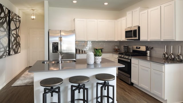 kitchen with appliances with stainless steel finishes, dark wood-type flooring, a sink, and white cabinetry