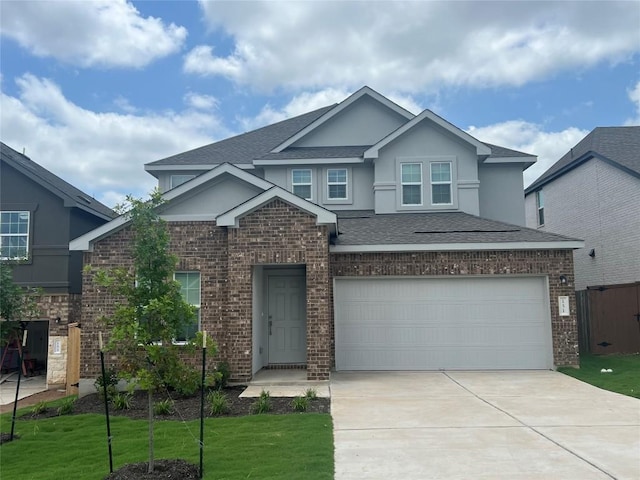 151 Cibolo Creek Loop, Bastrop, TX 78602 - view of front facade featuring concrete driveway, a garage, brick siding, a shingled roof, and stucco siding