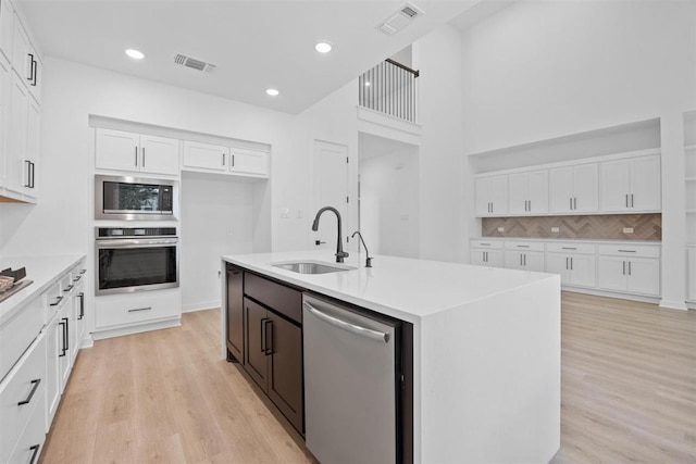5804 Kelly Kyle Ave, Georgetown, TX 78628 - kitchen featuring appliances with stainless steel finishes, white cabinetry, light wood-style floors, backsplash, and light countertops
